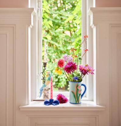 Bild av färgstark fönsterbräda med blommor och ljusstakar