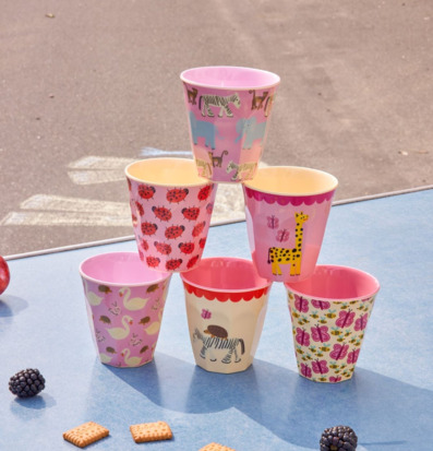 Bild med färgglada barnmuggar, bestick och picknickkex