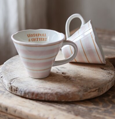 Bild av keramikmuggar i rustik miljö med varm hemtrevnad