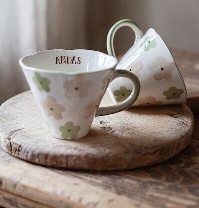 Bild med handgjorda muggar i pastell på rustikt träbord