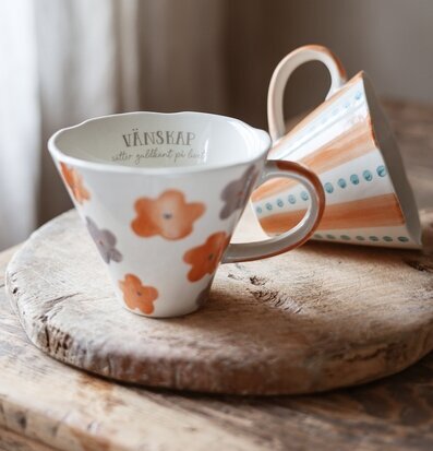 Bild av handgjorda keramikkoppar med blommor och träbricka
