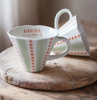 Bild av två porslinsmuggar på rustik träskiva i varm miljö