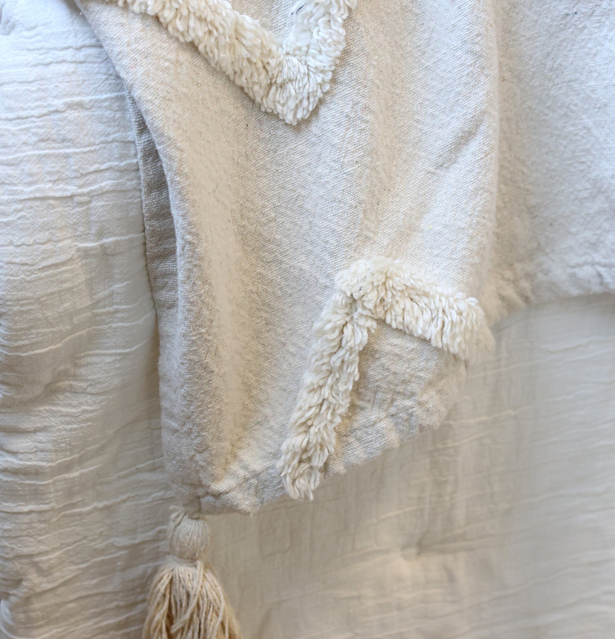Bild av sängöverkast i offwhite med tofs och texturdetaljer