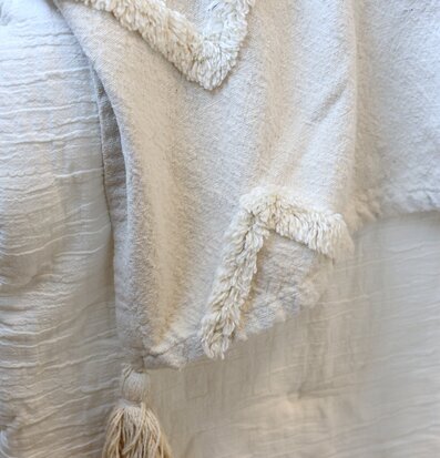 Bild av sängöverkast i offwhite med tofs och texturdetaljer