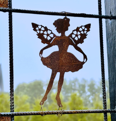 Bild av dansande älva i metall mot armeringsnät och natur