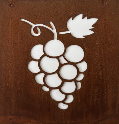 Bild på rostig metallskylt med utskurna vindruvor och blad
