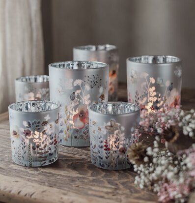 Bild av ljuslyktor med blommor i mjuka färger på rustikt bord