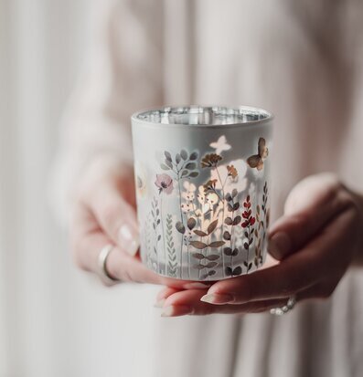 Bild på liten glaslykta med blomstermotiv och mjukt ljus