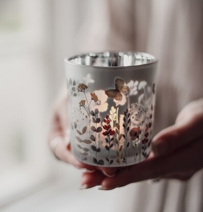 Bild av hand som håller dekorativ ljuslykta med sommarblommor