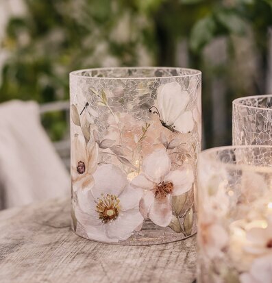 Bild: Ljuslykta i sprucket glas med blommor och fjärilar