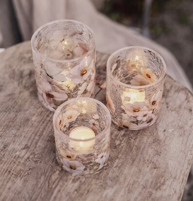 Bild av ljuslyktor i glas med blommor på rustikt träbord