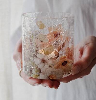 Bild av ljuslykta med blommor och fjärilar i mjuka färger