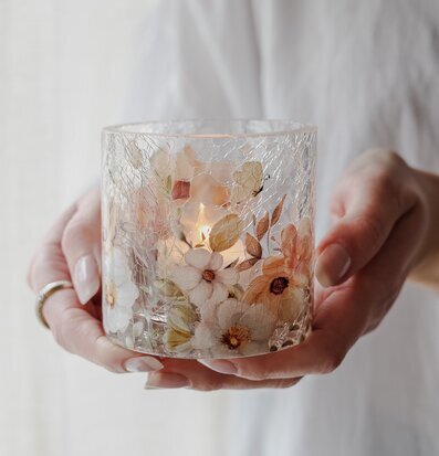 Bild på ljuslykta med blommor och sprucket glas i närbild