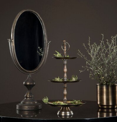 Bild med oval spegel, våningsfat och växt i harmonisk miljö
