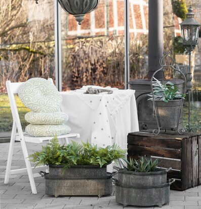 Bild på ljust uterum med glas, krukor i metall och växter