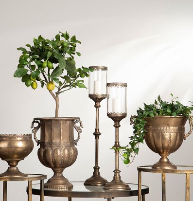 Bild med jordnära metallurnor, ljuslyktor och gröna växter