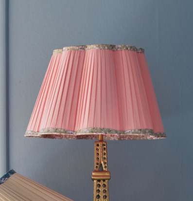 Bild på rosa lampskärm med blommig kant och gyllene lampfot