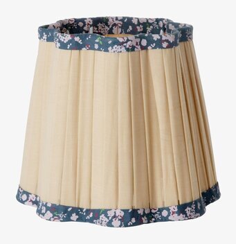 Bild av sandfärgad lampskärm med blå blommig kant och veck