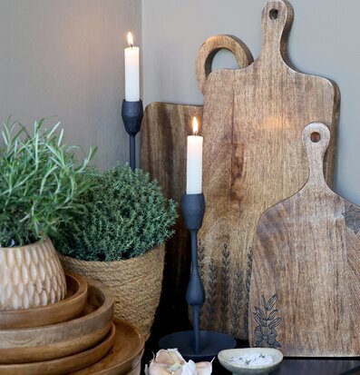 Bild med träbrickor, ljusstakar och kryddväxter i köksmiljö