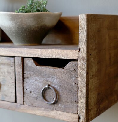 Bild på rustik trähylla med lådor och grön växt i keramikskål