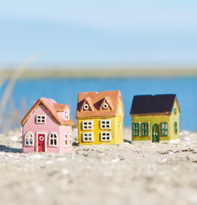 Bild med dekorativa små hus utomhus vid vatten och sand