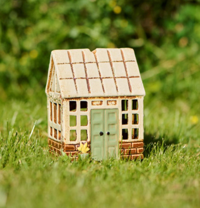 Bild av dekorativ ljuslykta som miniatyrhus i grön miljö