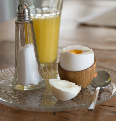 Bild av frukostdukning med äggkopp i trä och apelsinjuice