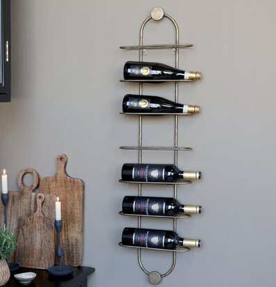 Bild av väggmonterat vinställ i mässing med stilren inredning