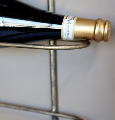 Bild på elegant vinställ i mässing med vinflaska på vägg