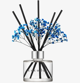 Bild på stilrena doftpinnar med blå blomster och glasflaska