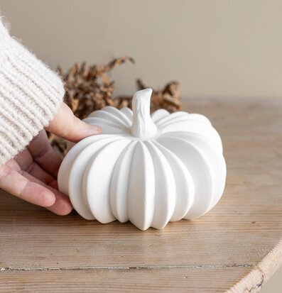 Bild av vit keramisk pumpa på träbord i höstig inredning