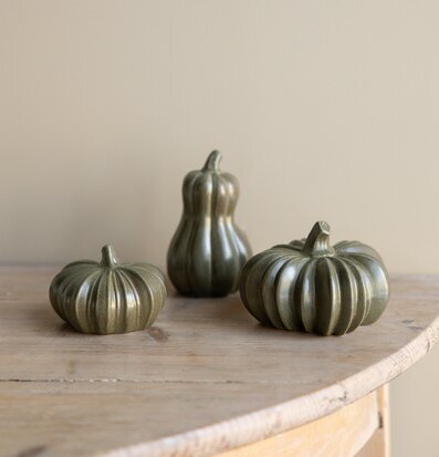 Bild på gröna keramikpumpor på ljust träbord i naturlig miljö