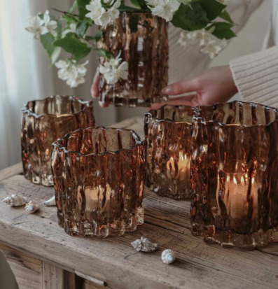 Bild med ljuslyktor i kastanjebrun glas och rustikt träbord