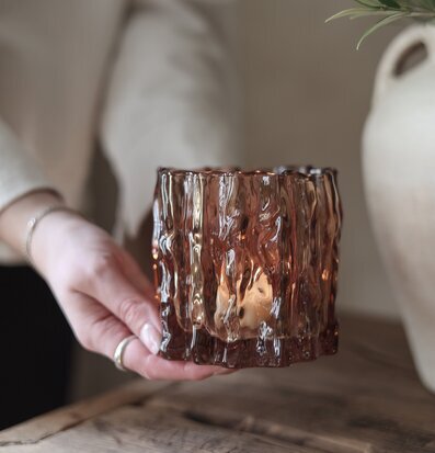 Bild av ljuslykta i kastanjebrunt glas och rustikt träbord