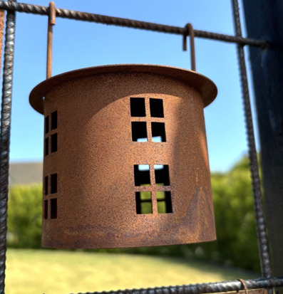 Bild på rostbrun trädgårdslykta i metall mot blå himmel