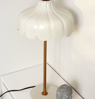 Bild av beige och guldig bordslampa med skulptur på sidobord