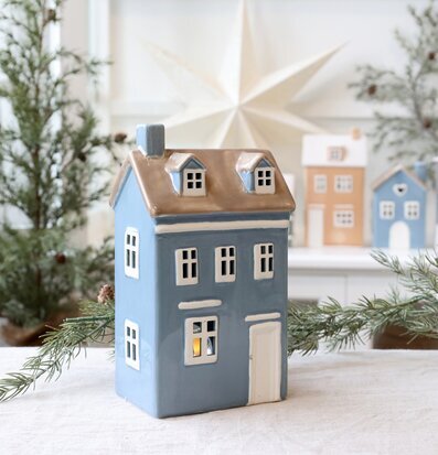 Bild av ljuslykta i keramikhus med vintergrönt och stjärna