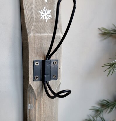 Bild på väggkrok med vintertema i trä och svart metall