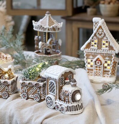 Bild av juligt tåg och pepparkakshus i mysig vintermiljö