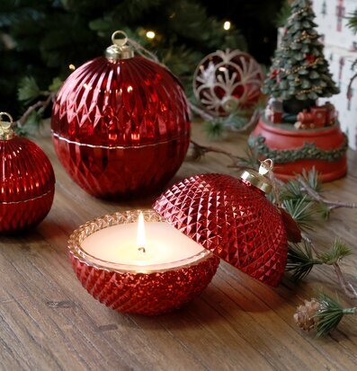 Bild av röd julkula med ljus och juldekoration i mysig miljö