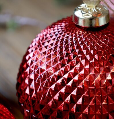 Bild av röd julkula med geometriskt mönster och guldfäste