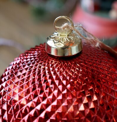 Bild på röd julkula med guldfäste och snöre i närbild