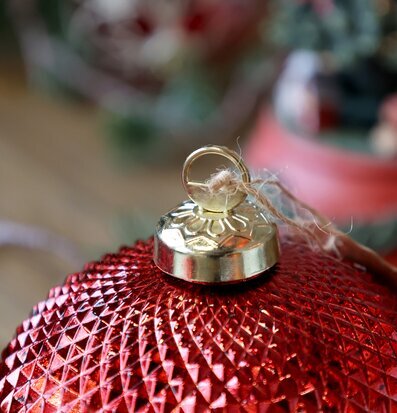 Bild på röd julkula med rutmönster och guldfäste i närbild