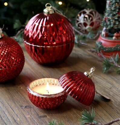 Bild av röd julkula med ljus och dekorerad gran i julmiljö