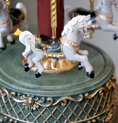 Bild på dekorativ speldosa med karusellhästar och gulddetaljer