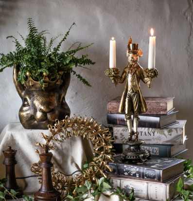 Bild av stilleben med guldljusstake, böcker och grönska