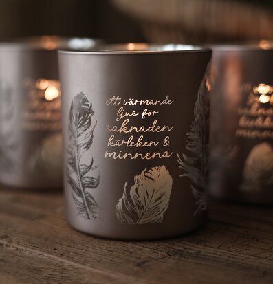 Foto: Ljuslykta med text, fjädrar och varmt sken