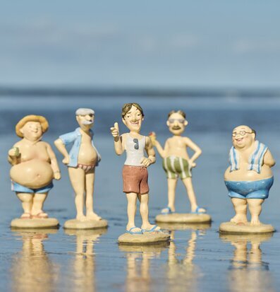 Foto: Strandfigurer på sand med speglingar i havet