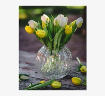 Foto: Tulpanbukett i glasvas på väderbitet träbord