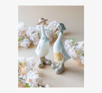 Bild på två ankskulpturer med blommor och stövlar